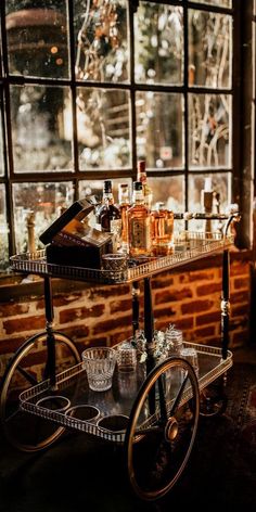 a bar cart in front of a window filled with liquor bottles and glasses on it