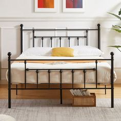 a white bed with black metal frame and headboard is in a room with hardwood floors