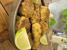 some fried food is in a bowl with lemon wedges