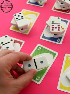 a person is playing with dices on a pink table