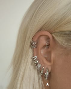 a woman with blonde hair wearing three different ear piercings on her left side and two silver stars in the middle