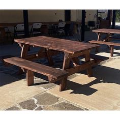 three picnic tables sitting on top of a stone floor next to each other in front of a building