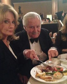 a man and woman sitting at a table with plates of food in front of them