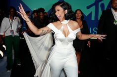 a woman in white jumpsuit dancing with her arms outstretched