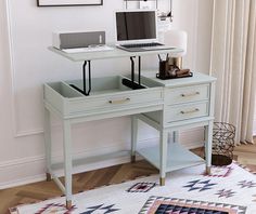 a desk with a laptop on it in front of a window and a rug next to it