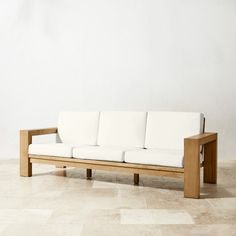 a white couch sitting on top of a tile floor next to a wooden frame wall