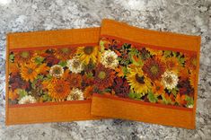 two placemats with sunflowers on them sitting on a marble counter top