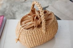 a wicker basket sitting on top of a white table next to a pink book