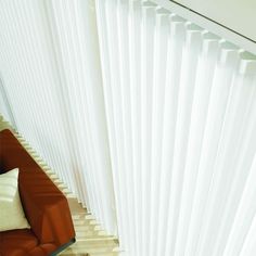 an overhead view of a living room with red couch and white vertical blinds on the wall