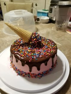 a cake with chocolate frosting, sprinkles and an ice cream cone on top