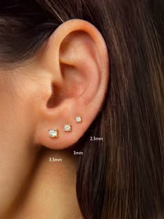 a woman's ear with three small diamond studs