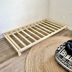 there is a small bed with wooden slats on the floor next to a potted plant