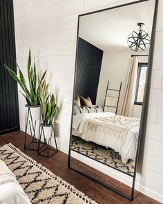 a large mirror sitting on top of a wooden floor next to a bed and potted plant