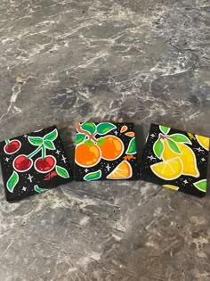 three coasters with fruit designs on them sitting on a marble counter top in front of a black background