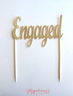 a cake topper that says engaged on it with two toothpicks sticking out of it