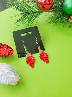 red beaded heart drop earrings on green table next to christmas tree and ornaments in background