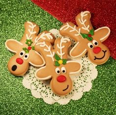 four decorated christmas cookies sitting on top of a doily covered table next to a red and green background