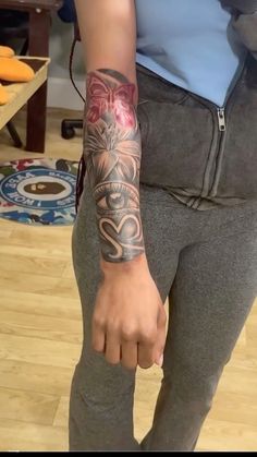 a woman with a tattoo on her arm and wrist standing in front of a table