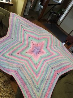 a crocheted blanket sitting on top of a couch next to a green chair