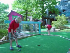 two people playing mini golf in a miniature golf course at a children's play area