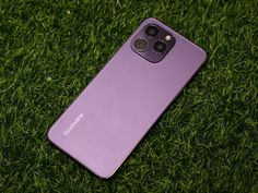 the back side of a purple samsung phone laying on green grass with its camera lens up