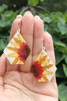 a hand holding a pair of earrings made out of beads