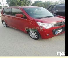 a red van parked in a parking lot next to another car and another black vehicle