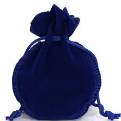 a small blue velvet bag with tassels on the front and side, sitting on a white surface