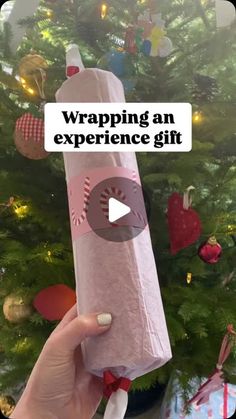 someone holding up a wrapped gift in front of a christmas tree with the words wrapping an experience gift