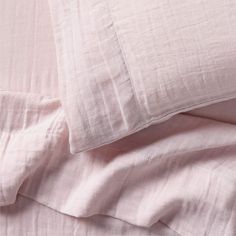 the sheets and pillow cases are made up in pale pink linens, with white piping on them