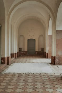 an empty hallway with tiled floors and arches