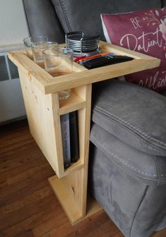 a wooden table with two glasses on it next to a gray couch and red pillow