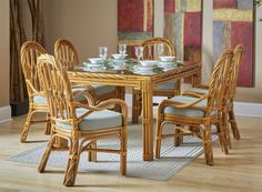 a dining room table with chairs and plates on top of it in front of a painting