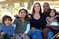 a woman and two children are sitting on a bench with their arms around each other