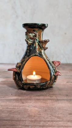 a lit candle in a vase on a wooden table