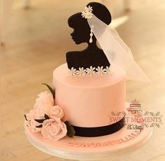 a wedding cake with a silhouette of a bride and groom on the top, decorated with flowers