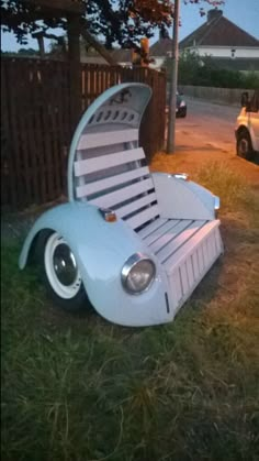 a lawn chair that is shaped like a buggy parked in the grass next to a fence