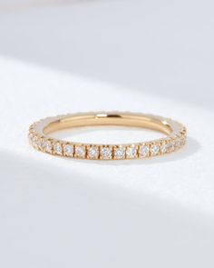 a yellow gold band with rows of diamonds on the inside and outside, set against a white background