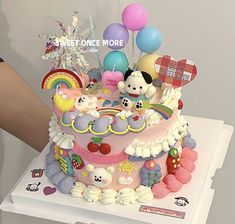 a birthday cake decorated with teddy bears, balloons and other decorations on a white box