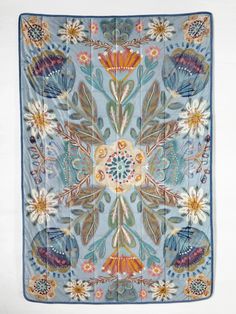 a blue and yellow square rug with flowers on the bottom, surrounded by smaller leaves