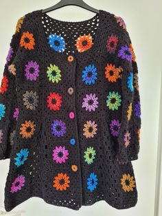 a black crocheted sweater with multicolored flowers on it