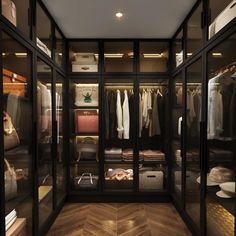 a walk in closet filled with lots of clothes and bags on top of wooden flooring