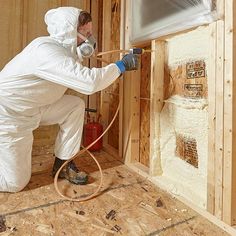 a man in white coveralls spray painting walls