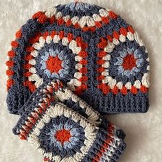 three crocheted hats and two mittens on a white surface, one is blue and the other is red