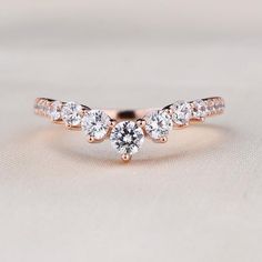 a rose gold ring with three diamonds on the top and bottom, sitting on a white surface