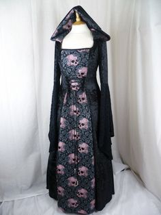 a black dress with skulls on it and a long sleeved coat over the shoulders