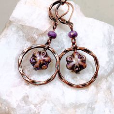 Purple glass flowers floating inside twisted copper rings make these Boho dangle earrings extra special. Copper rings frame the flower beads that have shades of purple, lavender and a Picasso finish.  Lightweight and versatile, these cute earrings will add a pop of color and sophistication to your look.  - Hypoallergenic ear wires (nickel and lead free). Select ear wire style.   - Free gift packaging included. Earrings arrive carded and in a gift bag. - Bohemian glass beads are handmade by artis Earthy Bohemian, Cottagecore Jewelry, Stone Bead Jewelry, Winter Earrings, Glass Bead Earrings, Flower Dangle Earrings, Lavender Flower, Copper Rings, Flower Beads