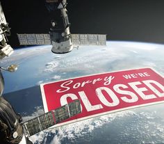 a red sign that says sorry we're closed hanging from the side of a space station