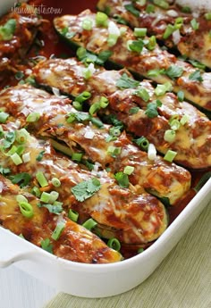 an enchilada casserole with meat and green onions in a white dish