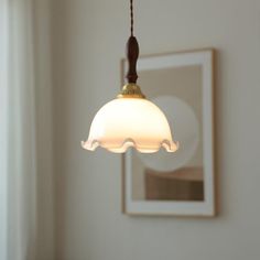 a white light hanging from a ceiling in a room with a mirror on the wall